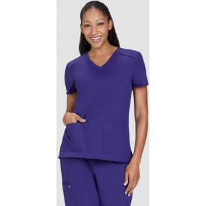 A purple medical scrub top with a V-neck and two front pockets, worn by a smiling model.