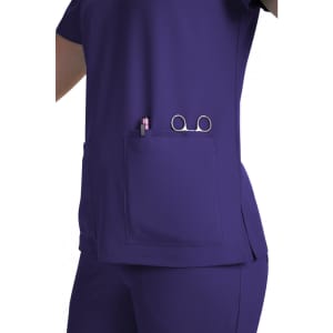 A purple medical scrub top features a pocket holding a pen and scissors, showcasing a practical design.