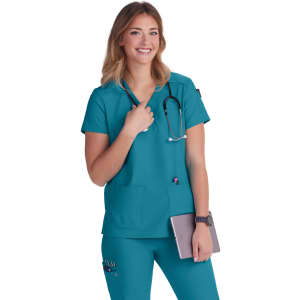 A medical scrub top in teal, featuring a round neckline, pockets, and a stethoscope. The model is smiling and holding a tablet.