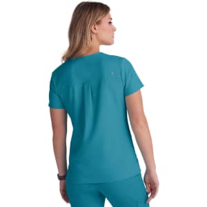 A teal women's top with short sleeves and a back pleat, featuring a brand logo.