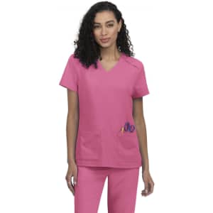 A medical scrubs top in pink, featuring a V-neckline and two front pockets. The model is smiling and wearing matching pants.