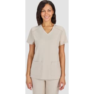 A beige medical scrub top with a V-neckline and two front pockets, worn by a smiling woman.