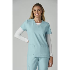 A scrubs top in light blue, featuring a V-neck and two front pockets, worn by a smiling model.