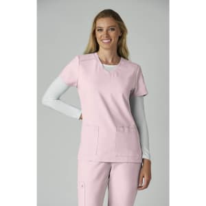 A healthcare top in pink, featuring a v-neck and two front pockets, worn by a smiling model.