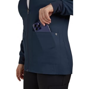 A women's navy jacket with a front zip and a pocket, where a smartphone is being placed. The jacket features a logo.