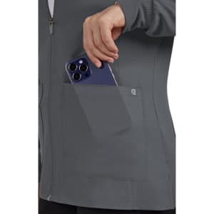 A grey women's jacket featuring a pocket, with a hand placing a phone inside. The jacket has a logo on it.