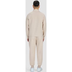 A beige men's jacket and matching pants are displayed from the back, featuring a simple design and a logo.