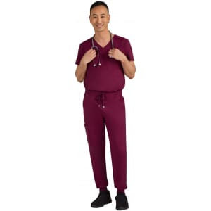 A man wearing burgundy scrubs and holding a stethoscope, with pockets on the pants. The outfit includes a V-neck top.