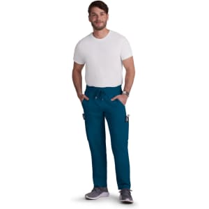 A man wearing teal Neuro Cargo Pants and a plain white t-shirt, with his hands in the pockets.