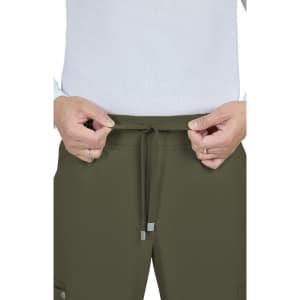 A person adjusts the drawstring of olive green cargo pants, featuring pockets and a flexible waistband.