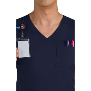 A navy scrub top featuring a chest pocket with pens and an ID badge holder. It has a logo on the badge.
