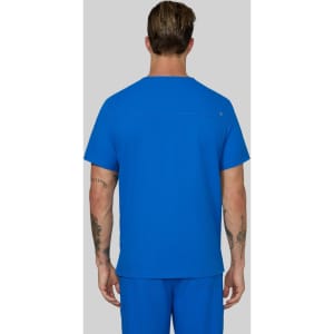 A man wearing a blue scrub top, viewed from behind, with matching blue scrub pants. The outfit includes a logo.