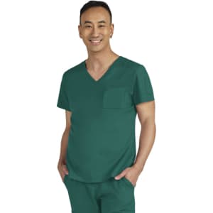 A man in a teal medical scrub top with a pocket, smiling against a neutral background. The outfit has branding details.