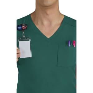 A green scrub top with a pocket containing pens and a blank name badge. The shirt features a V-neck design.