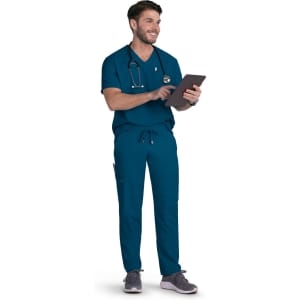 A man wearing teal scrubs and a stethoscope, holding a tablet and smiling.