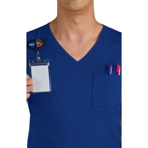 A navy blue scrubs top featuring a breast pocket with pens and a badge holder. The wearer is partially visible.