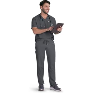A person wearing grey scrubs and a stethoscope, standing while holding a tablet. The outfit includes pockets and a logo.