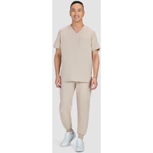 A man wearing a beige medical scrub set consisting of a V-neck top and jogger-style pants, paired with white shoes.