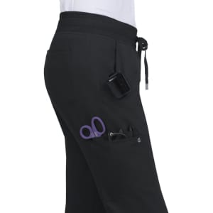 A pair of black jogger pants with pockets containing scissors and a small device. The pants feature a drawstring waist.