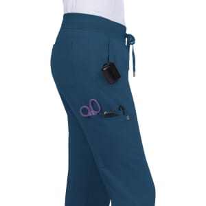A pair of teal jogger pants featuring pockets containing scissors and a small device, with a logo on the garment.