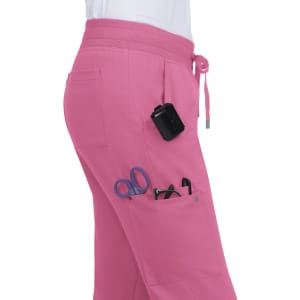 Pink jogger pants featuring multiple pockets, one holding scissors and various tools. The pants have an elastic waistband.