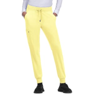Yellow jogger pants with a drawstring waistband and side pockets, worn with a long-sleeve white top and black shoes.