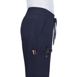 Atria Pant in navy blue, featuring side pockets with scissors and pens visible, and a drawstring waistband.