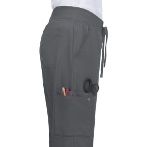 A grey pant featuring a drawstring waist and side pockets with pens and scissors visible. It has a logo on the fabric.
