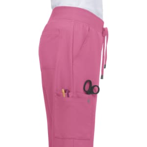 Atria Pant in bright pink with pockets containing pens and scissors, showcasing a side view.