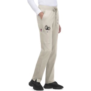 Atria Pant in light beige, featuring pockets and a drawstring waist. Includes scissors and pens in the side pockets.