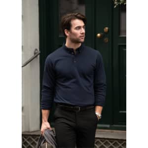 A navy blue polo shirt with a collar and button placket, modelled by a man in smart casual attire, holding a jacket.
