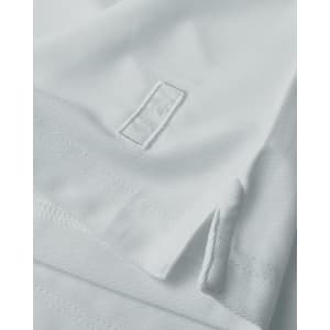 A white polo shirt featuring a hem split and a logo. The fabric has a textured appearance.