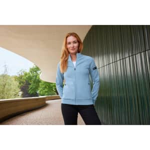 A light blue ladies zip jacket with a slim fit, featuring pockets and a logo, set against a modern architectural background.