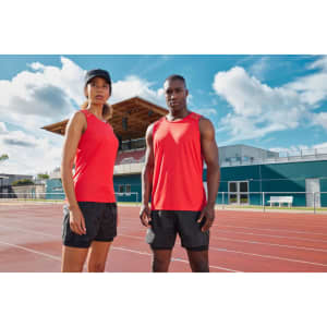 A red ladies' running tank, paired with a black running short, features one logo and is displayed outdoors on a track.
