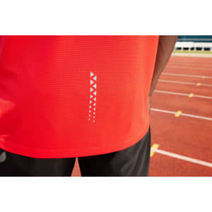 A red men's running tank with a patterned detail and a logo, displayed on a person near a running track.