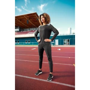 A long-sleeve ladies running shirt in black, featuring a fitted design, worn with matching black athletic pants.