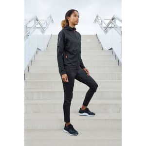 A black ladies running jacket features a hood and zippered pockets, paired with black athletic pants and shoes.