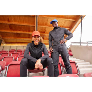 A black ladies running jacket is worn by a woman sitting, while a man in a matching black outfit stands beside her.