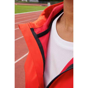 A close-up of a women's sports softshell jacket in vibrant red, featuring a hood and a black zipper.