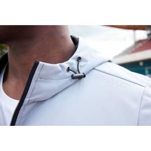 A softshell jacket in light grey, featuring a drawstring hood and a black zipper detail. It has a logo on the fabric.