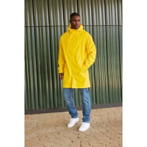 A unisex yellow raincoat features a hood and is styled over blue jeans and white sneakers. It has a logo.