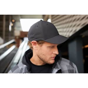 A black 6 panel workwear cap is displayed on a man, featuring a logo and a stylish, modern design.