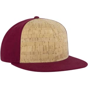 A snapback cap featuring a cork front and a burgundy fabric brim and sides. It includes a logo.