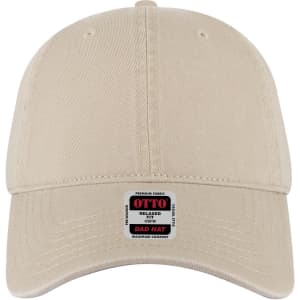 A beige 6-panel low profile dad cap featuring a logo on a badge at the front.