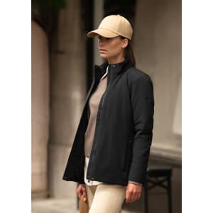 A woman wearing a black jacket with a beige cap, standing against a neutral background.