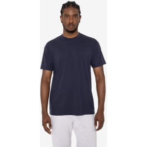 A man models a navy blue short sleeve cotton poly crew tee with a logo, paired with grey sweatpants.