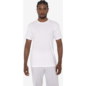 A white short sleeve cotton-poly crew tee on a model, paired with grey sweatpants. The tee features a logo.