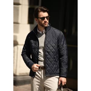 A navy quilted men's jacket features a zip front and a fitted design, worn with a light sweater and beige trousers.