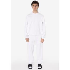 A model wearing white heavy fleece sweatpants with a matching white long-sleeve top and black slides.