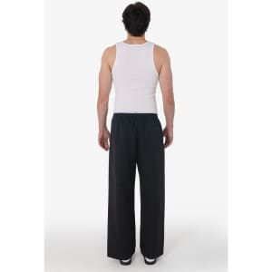 A person wearing straight leg heavy fleece track pants in black, with a white tank top. The image features a logo.